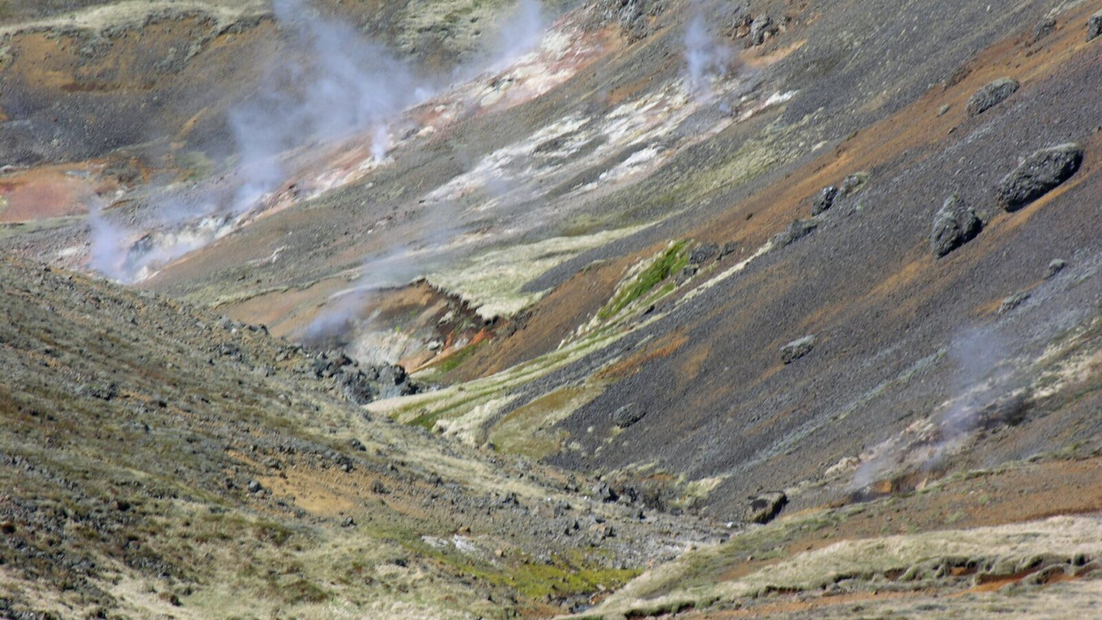 Steam vents rising from a rocky hillside