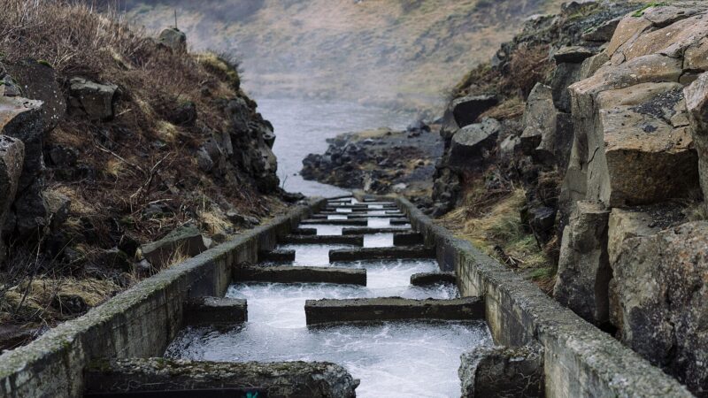 Concrete fish ladder with flowing water between rocky banks (Suðurland)