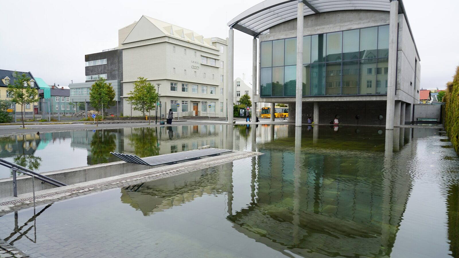 Modern concrete building beside reflecting pool and plaza (Reykjavík)