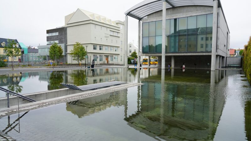 Modern concrete building beside reflecting pool and plaza (Reykjavík)