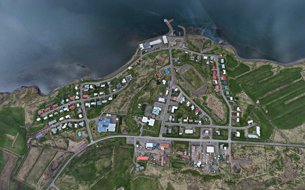 Aerial view of a small coastal town with harbour and houses (Dalabyggð)
