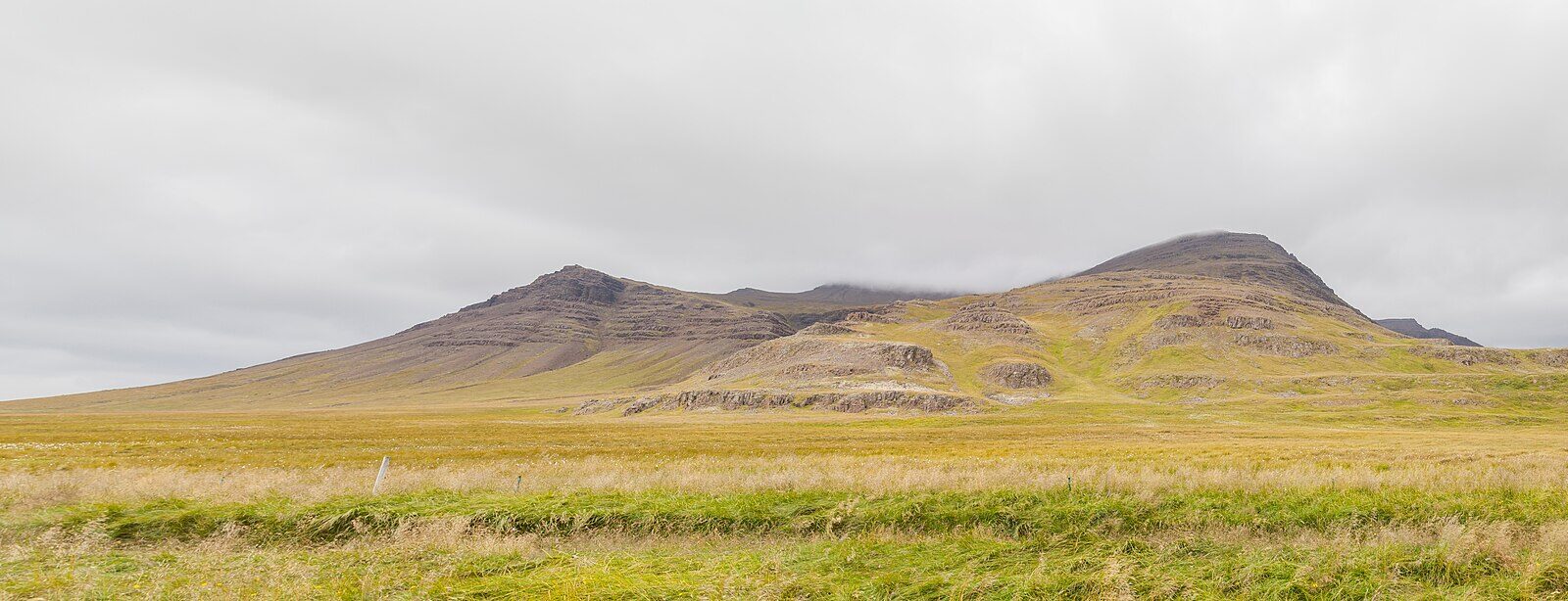 Wide grassland in front of a low mountain ridge (Eyja- og Miklaholtshreppur)