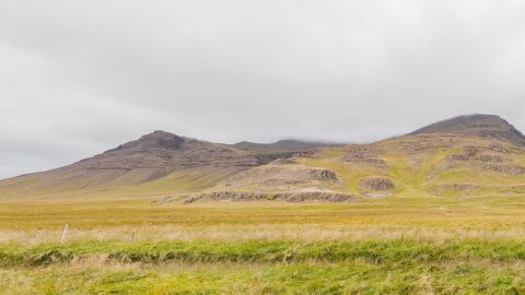 Wide grassland in front of a low mountain ridge (Eyja- og Miklaholtshreppur)