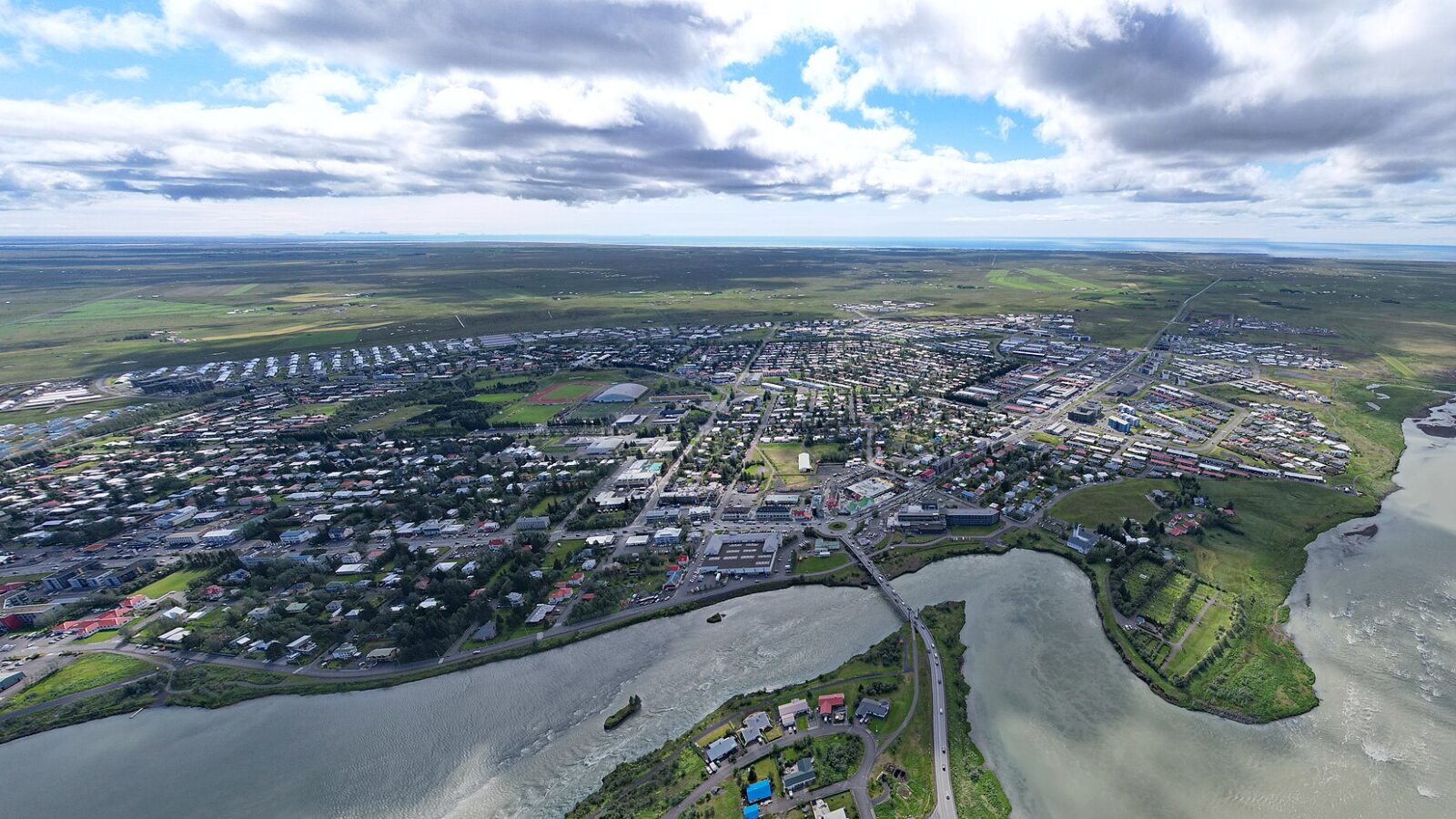 Aerial view of town, river and coastal plain under a cloudy sky