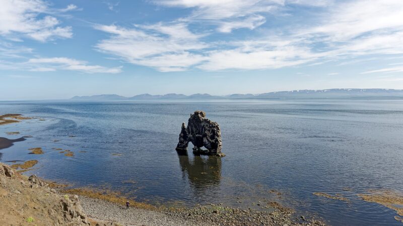 Sea stack rising from coastal waters with pebble beach (Hvítserkur)