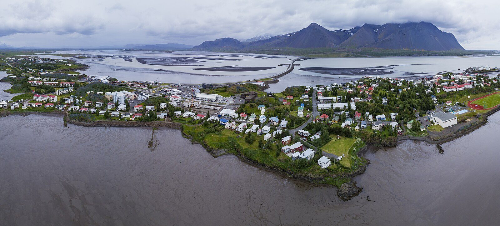 Panoramic aerial view of a coastal town with mountains and tidal flats (Borgarnes)