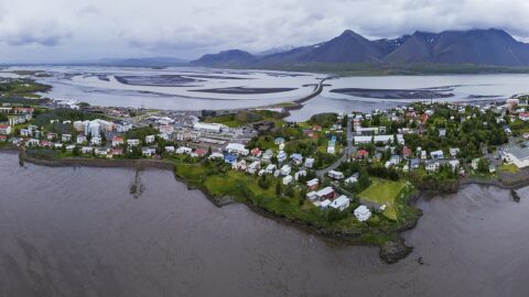 Panoramic aerial view of a coastal town with mountains and tidal flats (Borgarnes)