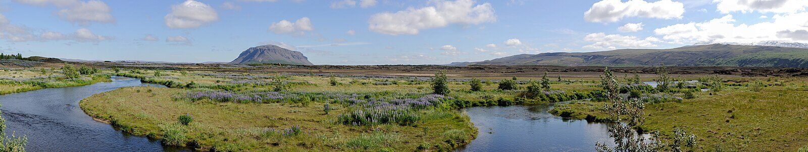 Meandering river through wetlands with distant low mountains (Ásahreppur)