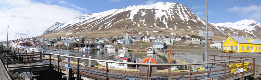Quayside and wooden walkways with yellow building and mountains (Fjallabyggð)