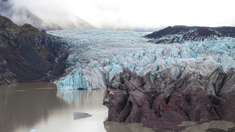 A glacier tongue ending in a lagoon under dark skies