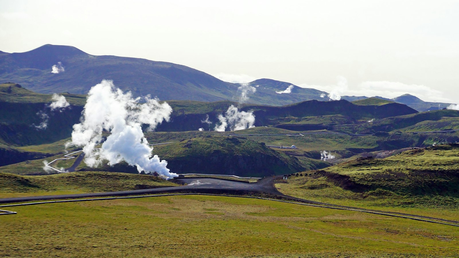 A geothermal power plant steaming in a green valley
