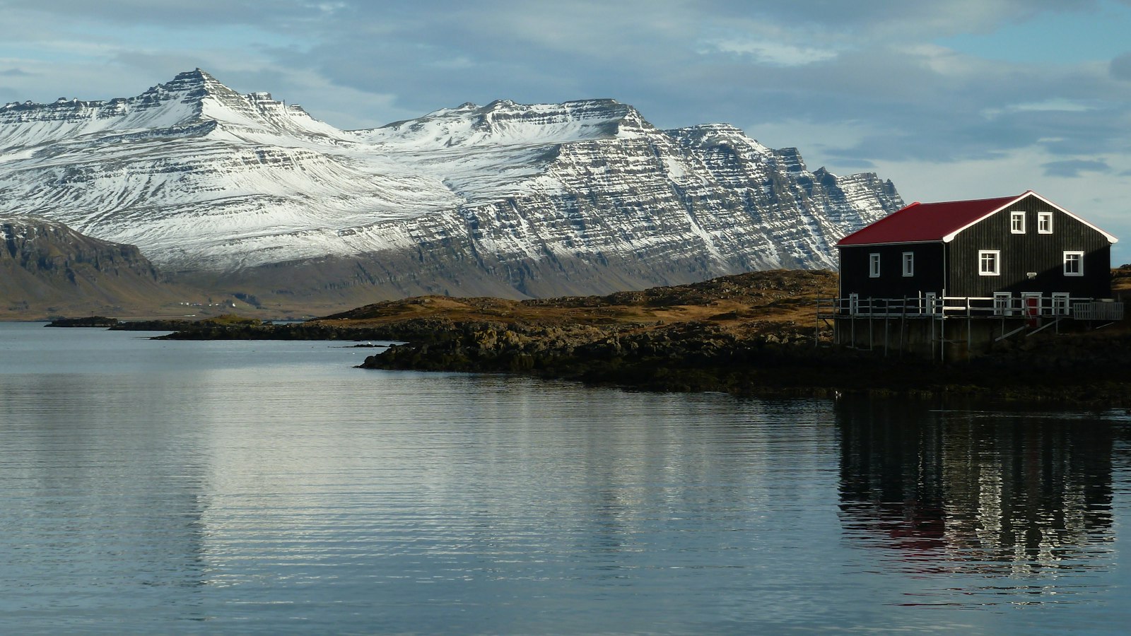 House on the shore of a lake with mountains behind