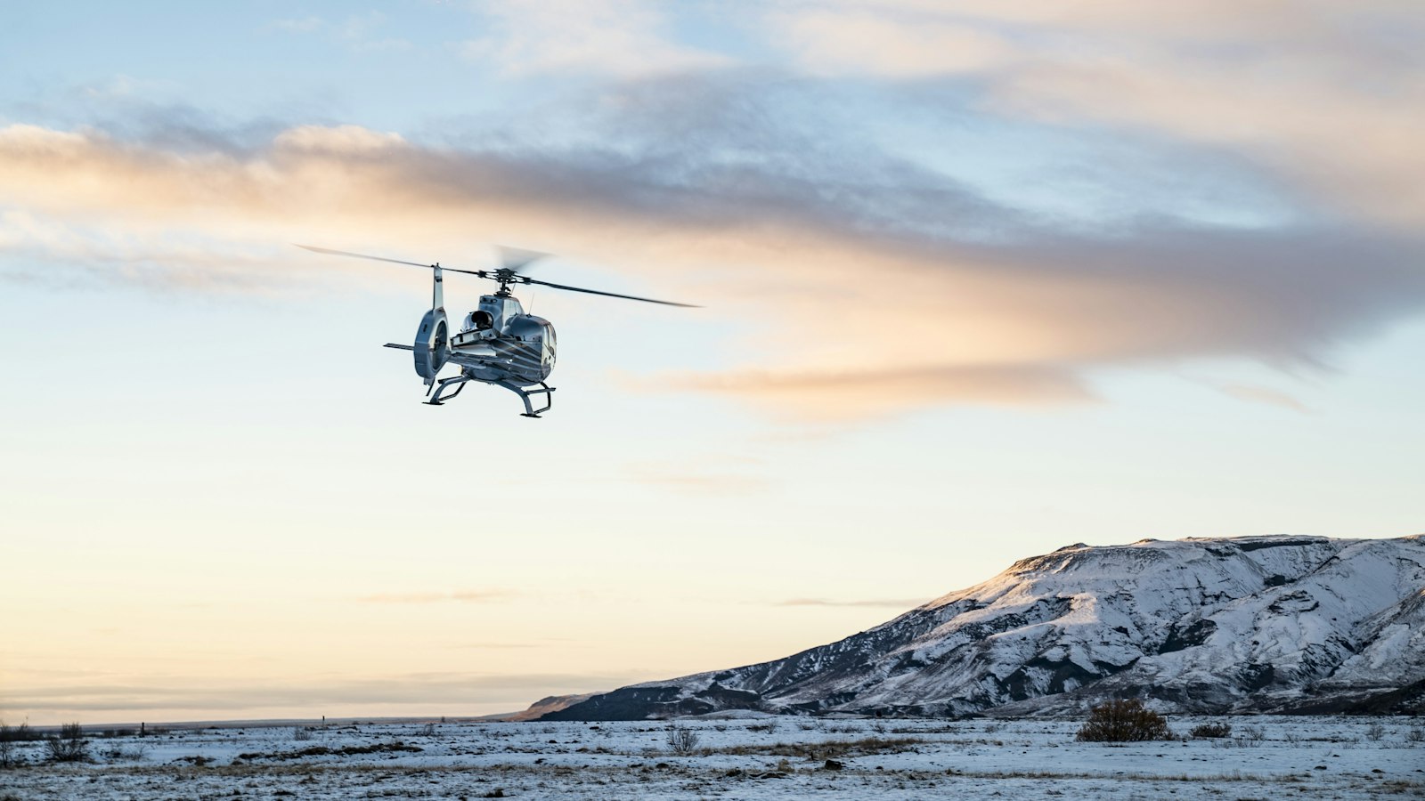 A helicopter flying over snowy mountains