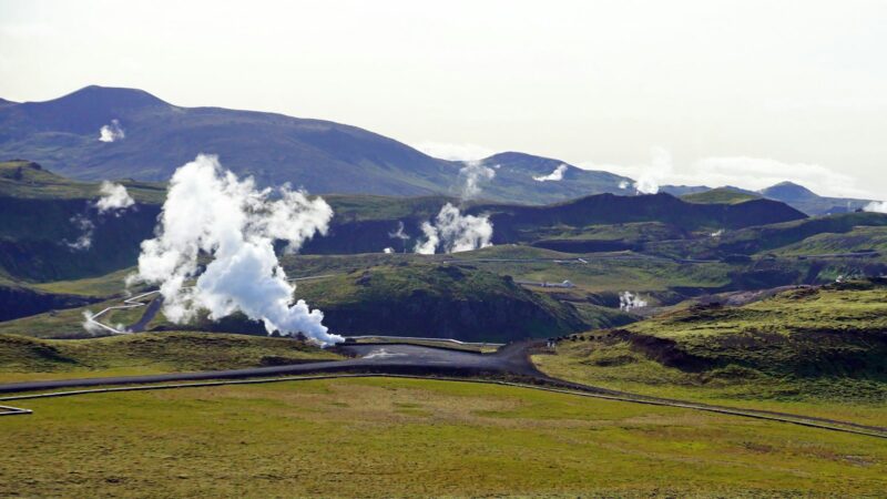 A geothermal power plant steaming in a green valley