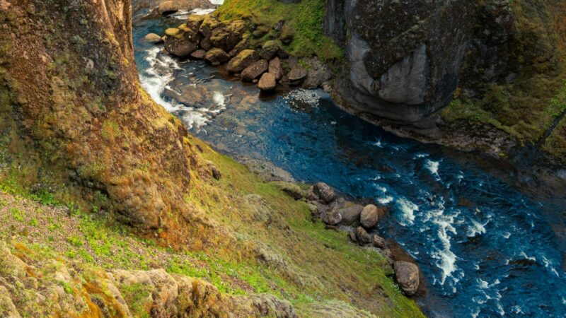 Deep canyon with river between moss-covered cliffs