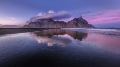 Vestrahorn mountain reflected in wet black sand