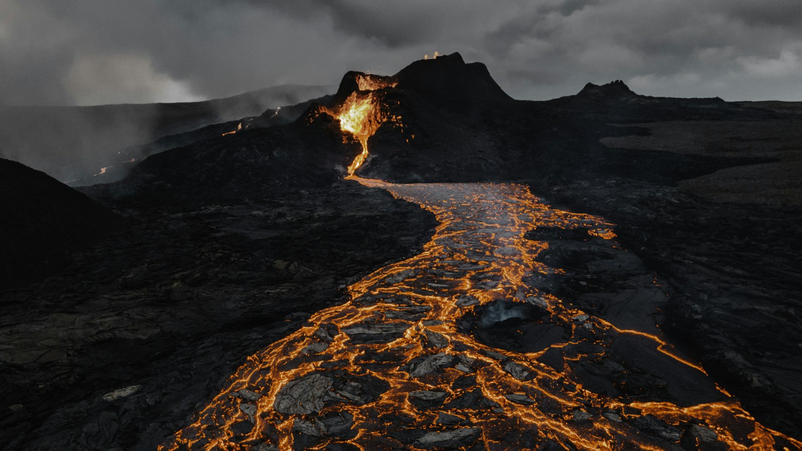 Molten lava flowing across dark rock at Fagradalsfjall